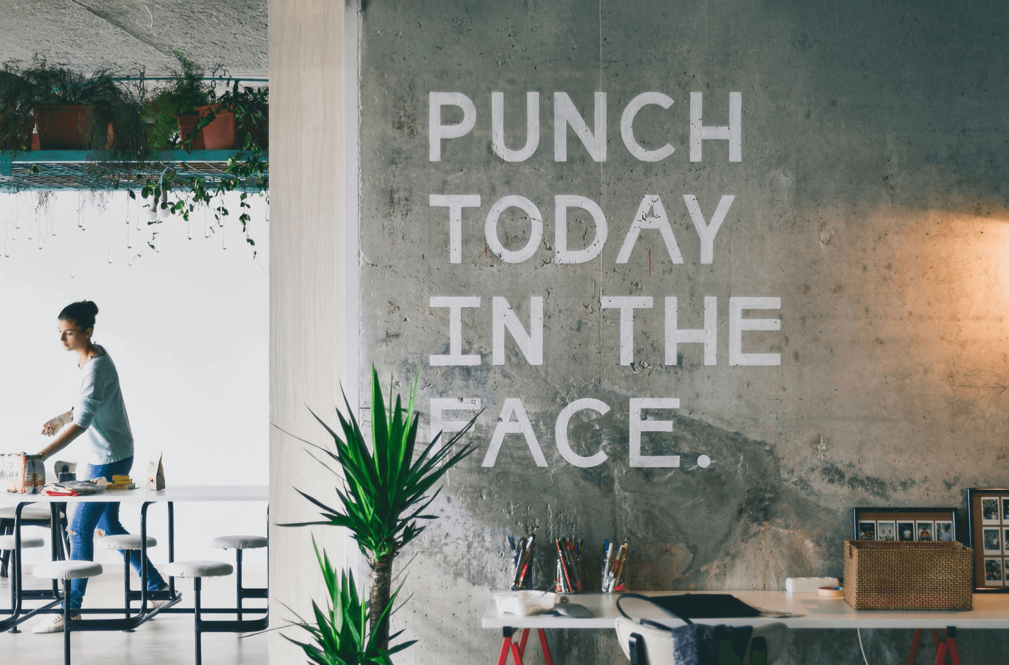 a modern startup office space with the words Punch today in face stenciled on the concrete wall