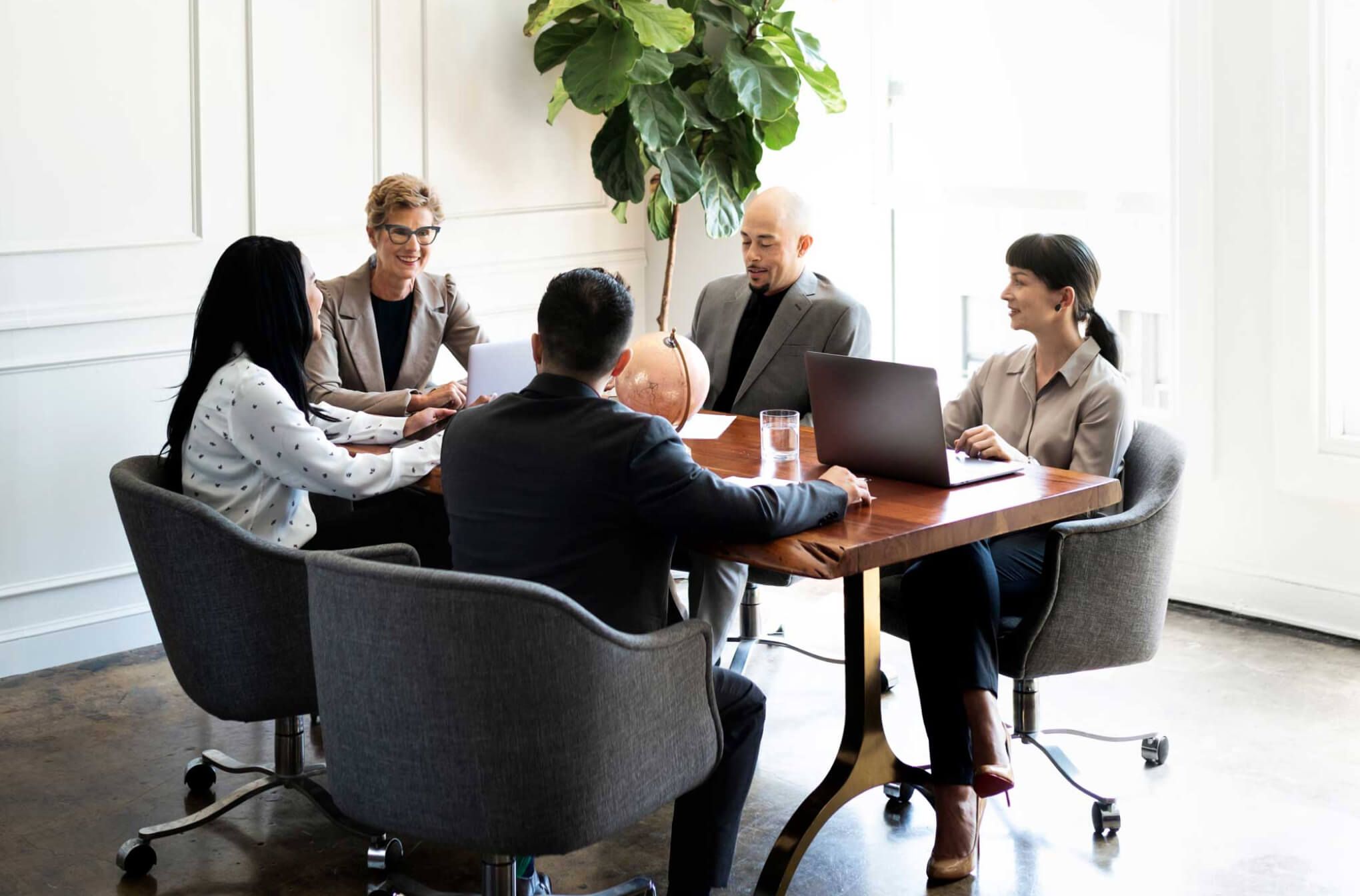 team of 5 sitting around a table in a meeting room